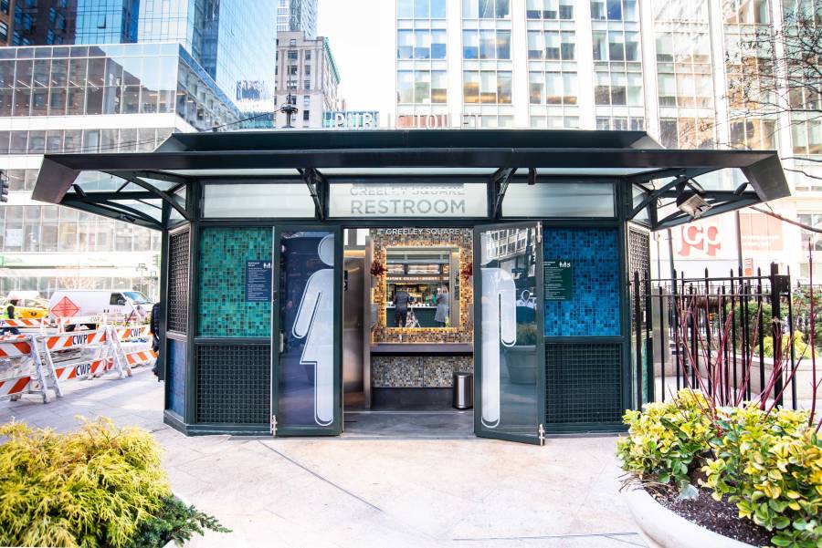 The newly renovated Greeley Square bathroom in New York City with door open, flowers, and park environs in the middle of the city.