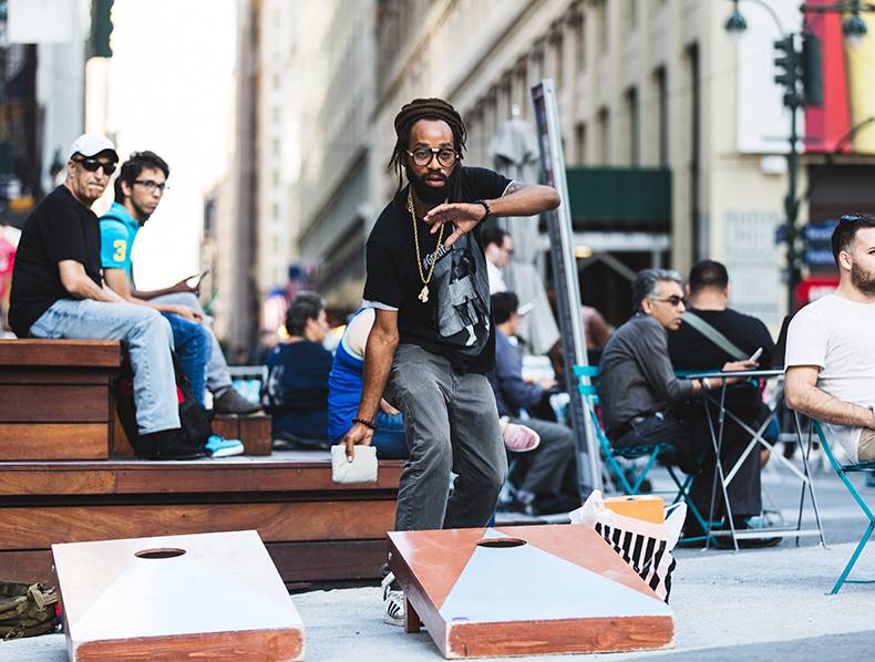 man playing cornhole in plaza