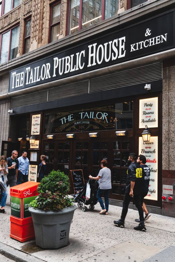 People walk past the entrance to Tailor Public House.